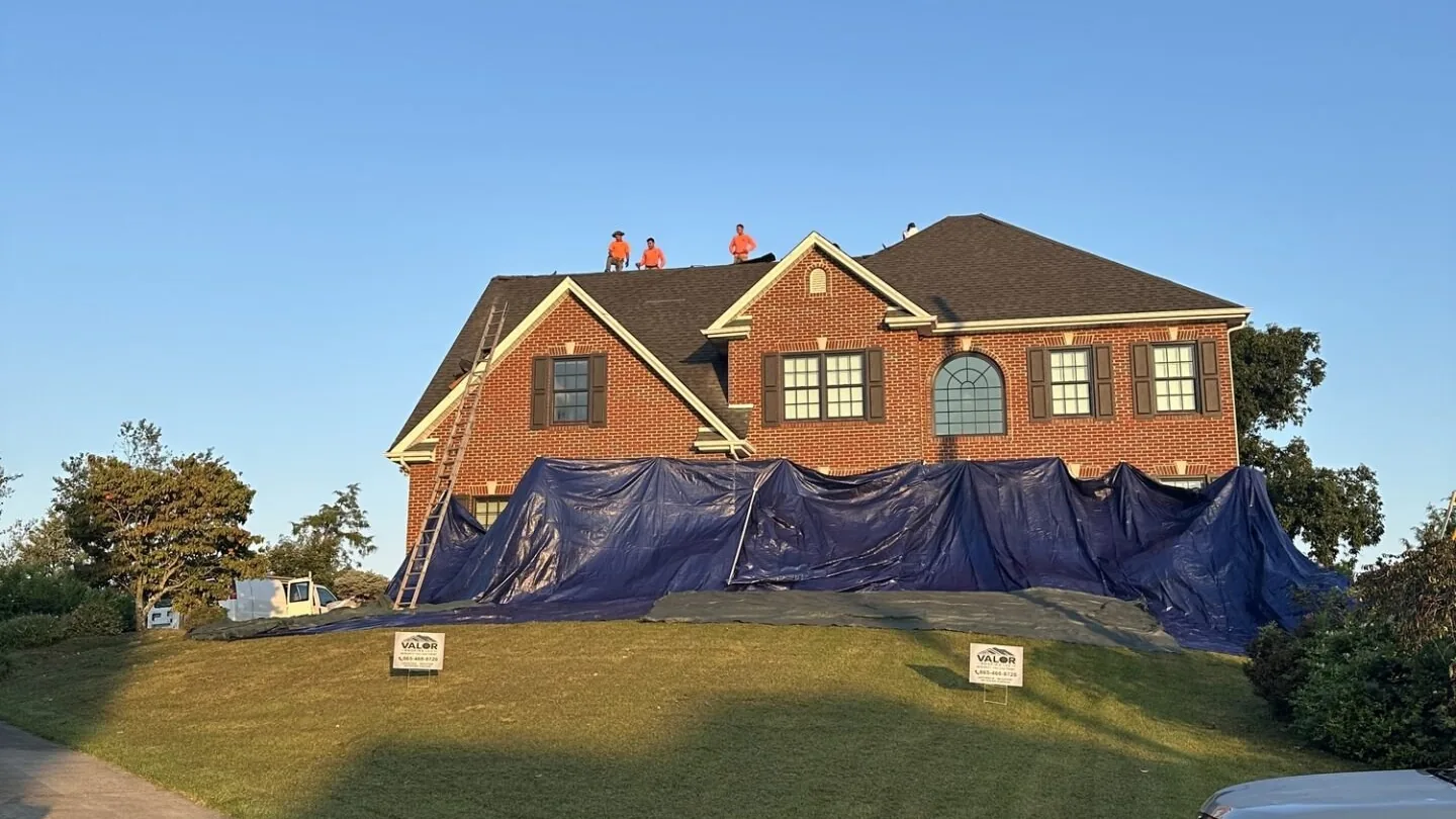 Home wrapped in protective tarps while a crew works on the roof